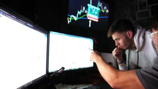 Two traders engaged in cryptocurrency analysis, focused on multiple screens displaying market data, showcasing the dynamic environment of digital trading and decision-making processes