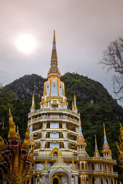 Golden pagoda spire of Wat Tham Suea Tiger Cave Temple under cloudy sky in Krabi, Thailand