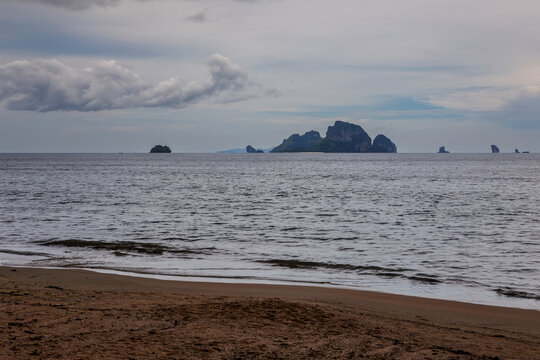 Ao Nang beach and tropical limestone cliffs landscape under cloudy sky in Krabi, Thailand