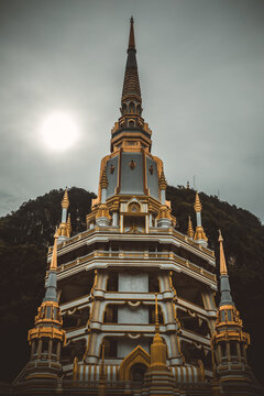 Golden pagoda spire of Wat Tham Suea Tiger Cave Temple under cloudy sky in Krabi, Thailand