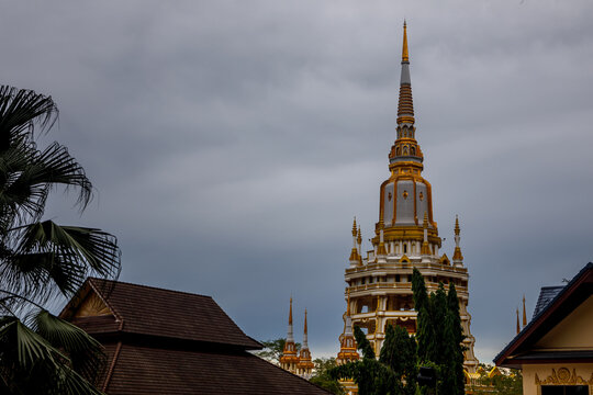 Golden pagoda spire of Wat Tham Suea Tiger Cave Temple under cloudy sky in Krabi, Thailand