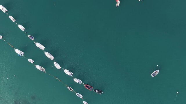 Aerial view of an overhead view of numerous boats and yachts moored in neat rows in the turquoise waters of Port de Ploumanac'h, located in Perros-Guirec, Brittany, France.