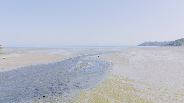 Wide static shot of Binic beach in Brittany, France, during low tide on a clear summer day.