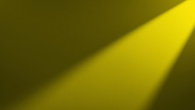 Yellow spotlight beam shining diagonally across dark studio background