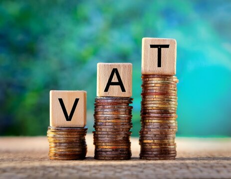 vat concept wooden blocks spelling out vat stand atop stacks of coins representing the financial concept of value added tax and its economic impact