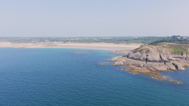 Aerial view of the clear blue waters and rugged rocky coastline of Anse du Croc in Frehel, Brittany, France.