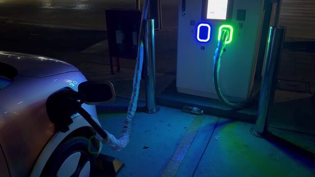 BANGKOK, THAILAND - APRIL 2026 : Close-up shot of hand plugging charging cable into electric vehicle. Southeast Asian clean energy, sustainable EV lifestyle and eco transport concept video.