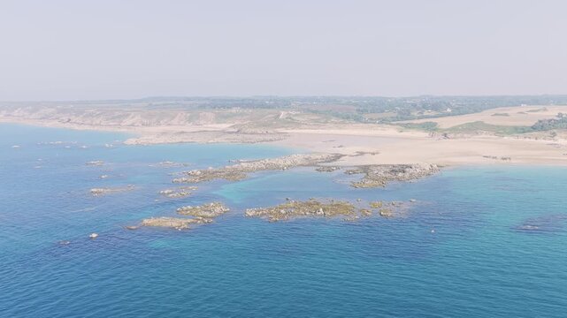 Aerial view of Anse du Croc in Frehel, Brittany, France, showcasing a wide sandy beach, turquoise sea, and rocky outcrops along the coastline.