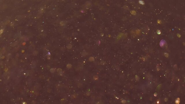 Defocused twinkle particles. Glitter light. Yellow sparks spiral stream on dark abstract background. Color flicker dots blur texture.