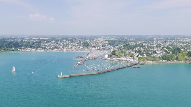 Aerial view of Binic, a coastal town in Brittany, France, showcasing the marina, harbor, and waterfront with numerous boats and sailboats on a clear summer day.