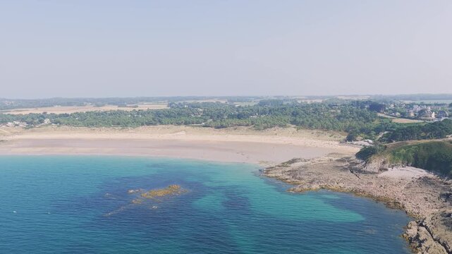 Aerial view of the expansive sandy beach and rugged rocky coastline of Anse du Croc in Frehel, Brittany, France.