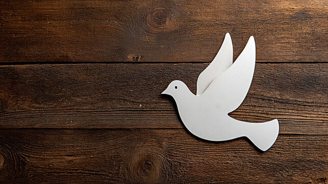 White wooden dove silhouette with outstretched wings positioned on a rustic wooden surface, symbolizing peace and tranquility in a natural setting