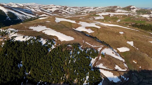 Top-down drone video view moving towards green trees in snowy mountains