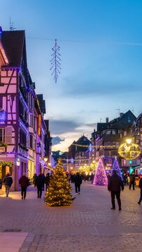 Colmar Christmas Market at twilight with traditional half-timbered houses and festive lights.