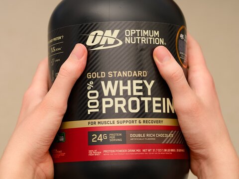 Tambov, Russian Federation - January 30, 2026 Black jar of Optimum Nutrition Whey Protein in person hands