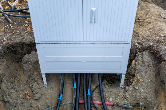Underground power cables entering an electrical distribution cabinet during construction work in a residential area in Germany. The image illustrates electricity distribution, underground power infras