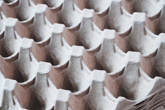 Close-up of cardboard egg cartons fills  frame. Brown and white colors define pattern. Curved compartments form uniform grid. Smooth surface indicates clean material