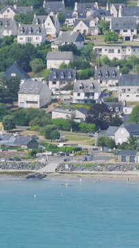 Aerial view of the coastal town of Binic in Brittany, France, showing traditional Breton houses, a sandy beach, a Ferris wheel, and seaside attractions along the waterfront.