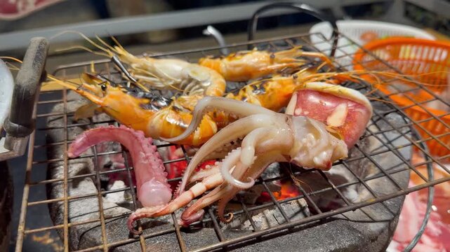 PATTAYA, THAILAND - APRIL 2026 : View of cooking various meats, seafood, fish balls and vegetables on Mookata combination hot pot and BBQ pan. Local Thai food culture and dining lifesty