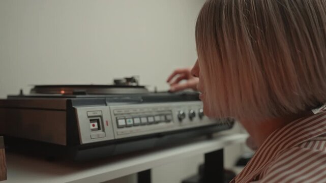 Woman tunes stereo. Music enthusiast calibrates old amplifier. Focused individual finetunes vintage audio equipment. Person carefully manipulates antique stereo controls in home setting