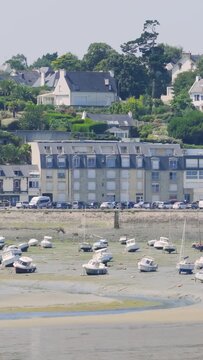 Static wide shot of small boats resting on the muddy seabed at low tide in the port of Binic, Brittany, France.