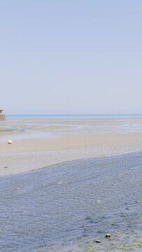 Wide shot of Binic beach in Brittany, France, at low tide on a clear summer day.