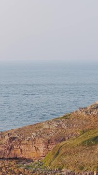 Wide shot of the rugged rocky coastline and grassy cliffs of Ilot Saint Michel near Erquy in Brittany, France.