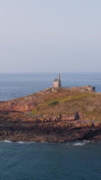 Aerial view of the small historic chapel on Ilot Saint Michel, a rocky tidal island off the coast of Erquy in Brittany, France.