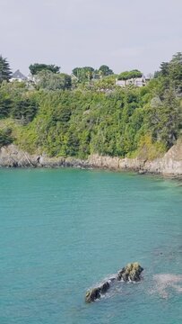 A scenic view of the lush green cliffs overlooking the turquoise waters of the sea in Binic, Brittany, France.