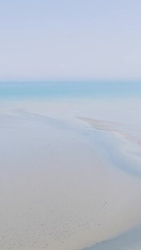 Aerial view of a wide sandy beach meeting calm blue sea in Binic, Brittany, France.
