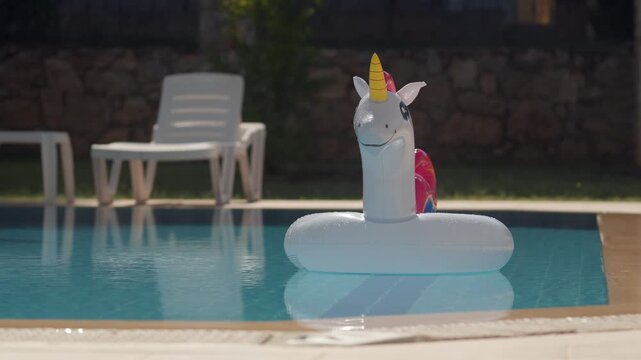 Unicorn float in the pool with lounge chairs nearby and a sunny day in the background