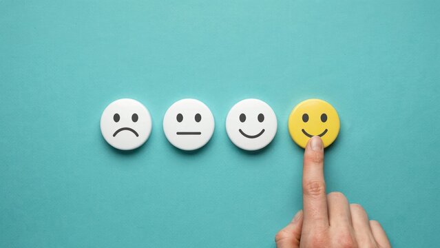 Hand selecting a yellow smiley face on a teal background