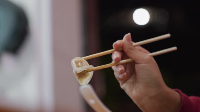 Night moonlit hand holding dumpling against soft sky glow, chopsticks frame delicate wrapper, quiet outdoor snack moment with subtle bokeh and crisp texture, intimate latenight atmosphere