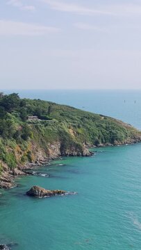 A scenic coastal landscape featuring rugged green cliffs meeting the turquoise waters of the sea, captured near Binic in Brittany, France.