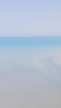 A tranquil aerial shot overlooking the sandy shoreline and clear blue waters of Binic beach in Brittany, France.