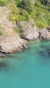 Aerial view of rugged coastal cliffs and clear turquoise sea in Binic, Brittany, France.