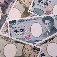 Japanese yen money bills pile on table. Japan banknotes of JPY currency close up. © Larysa