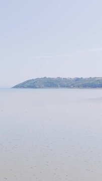 A tranquil wide shot of the sandy beach and calm waters at Binic, located on the Brittany coast of France.