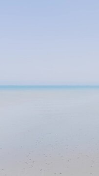 Minimalist wide shot of a serene sandy beach and calm sea under a clear blue sky at Binic, Brittany, France.