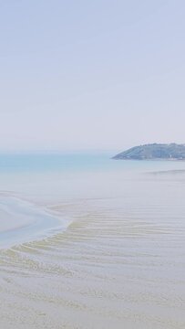 A serene wide shot of Binic beach on the Brittany coast of France during low tide.