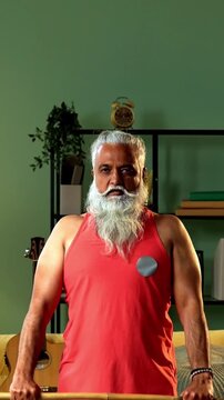 Indian mid age stylish bearded man doing exercise using stick, rod or staff at home, fitness conscious mature male performing strength and mobility workout showing agility and determination