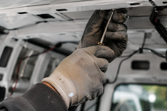 Worker installing roof skylight during camper van conversion