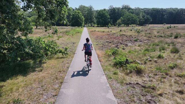 Woman cycling through a green woodland in summer
