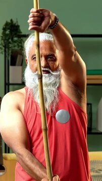 Indian mid age stylish bearded man doing exercise using stick, rod or staff at home, fitness conscious mature male performing strength and mobility workout showing agility and determination