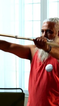 Indian mid age stylish bearded man doing exercise using stick, rod or staff at home, fitness conscious mature male performing strength and mobility workout showing agility and determination