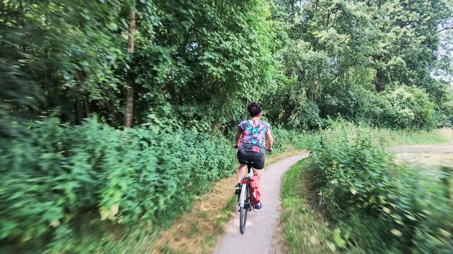 Woman cycling through a green woodland in summer

