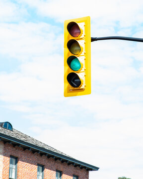 Green stoplight highlighted agains a blue and white sky.