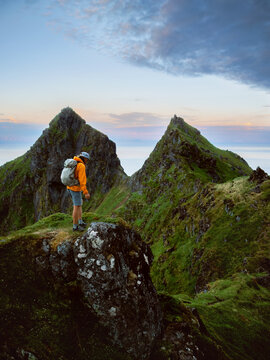 Man hiker climbing mountains solo travel in Norway healthy lifestyle active adventure summer vacations tour outdoor, backpacker tourist standing on cliff enjoying Lofoten islands view freedom getaway