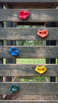 Wooden climbing wall featuring colorful plastic holds, providing an engaging and active experience for children in an outdoor playground environment, promoting play and physical activity