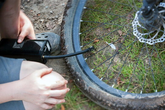 a kid pumping a bike wheel with a hand portable pump, outddoor close up